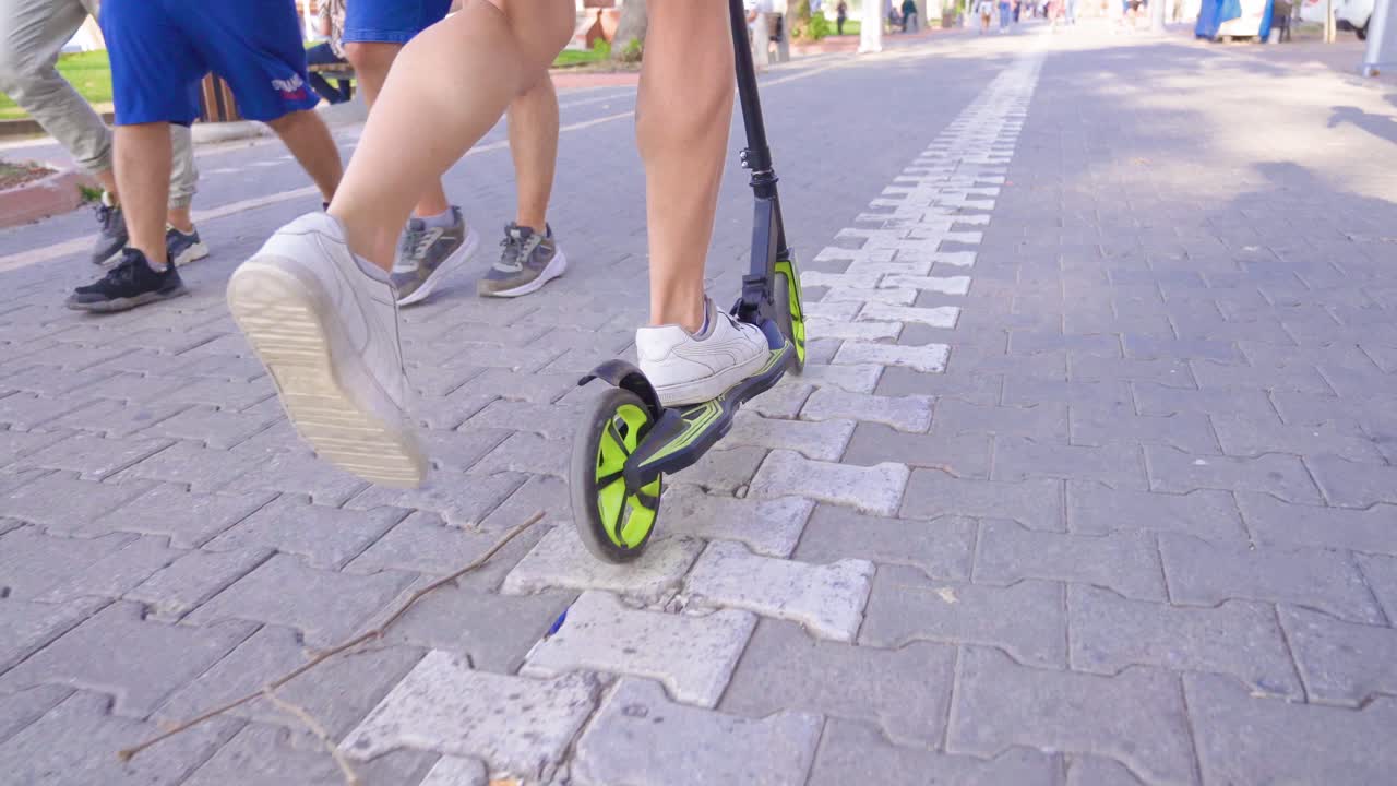 Male feet riding scooter in the city.