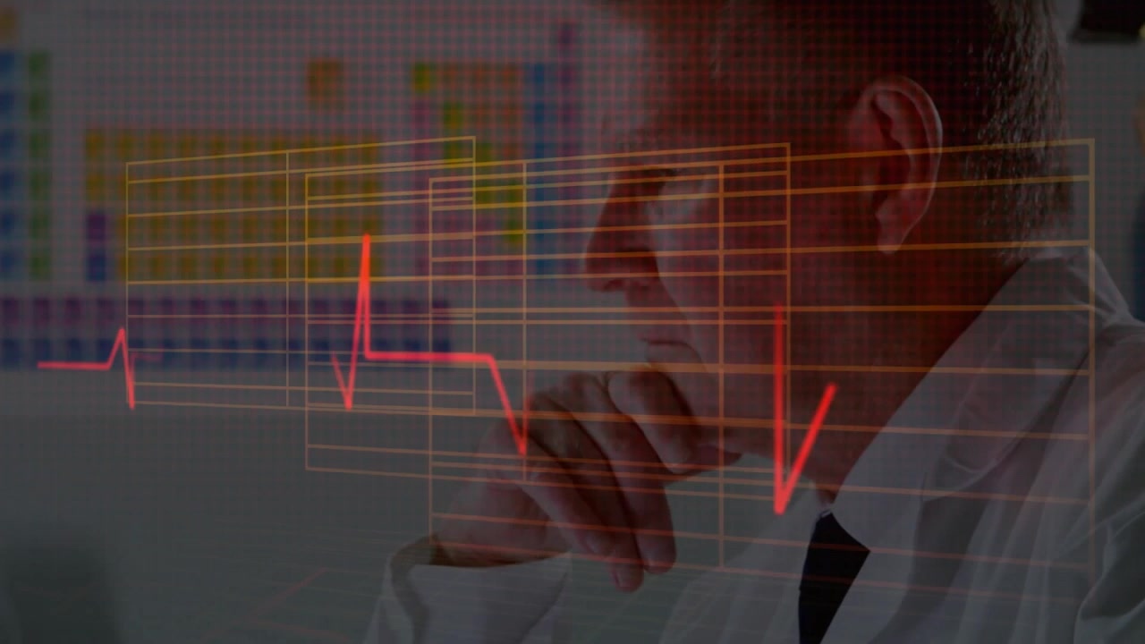 Clinico senior che digita e poi si ferma, attivando pannelli ECG rossi mentre analizza dati cardiaci.