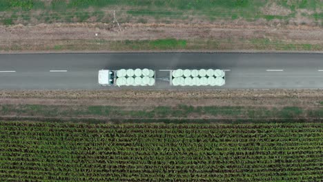 truck with silage bales as load moving on road, transporting fodder for livestock, top down