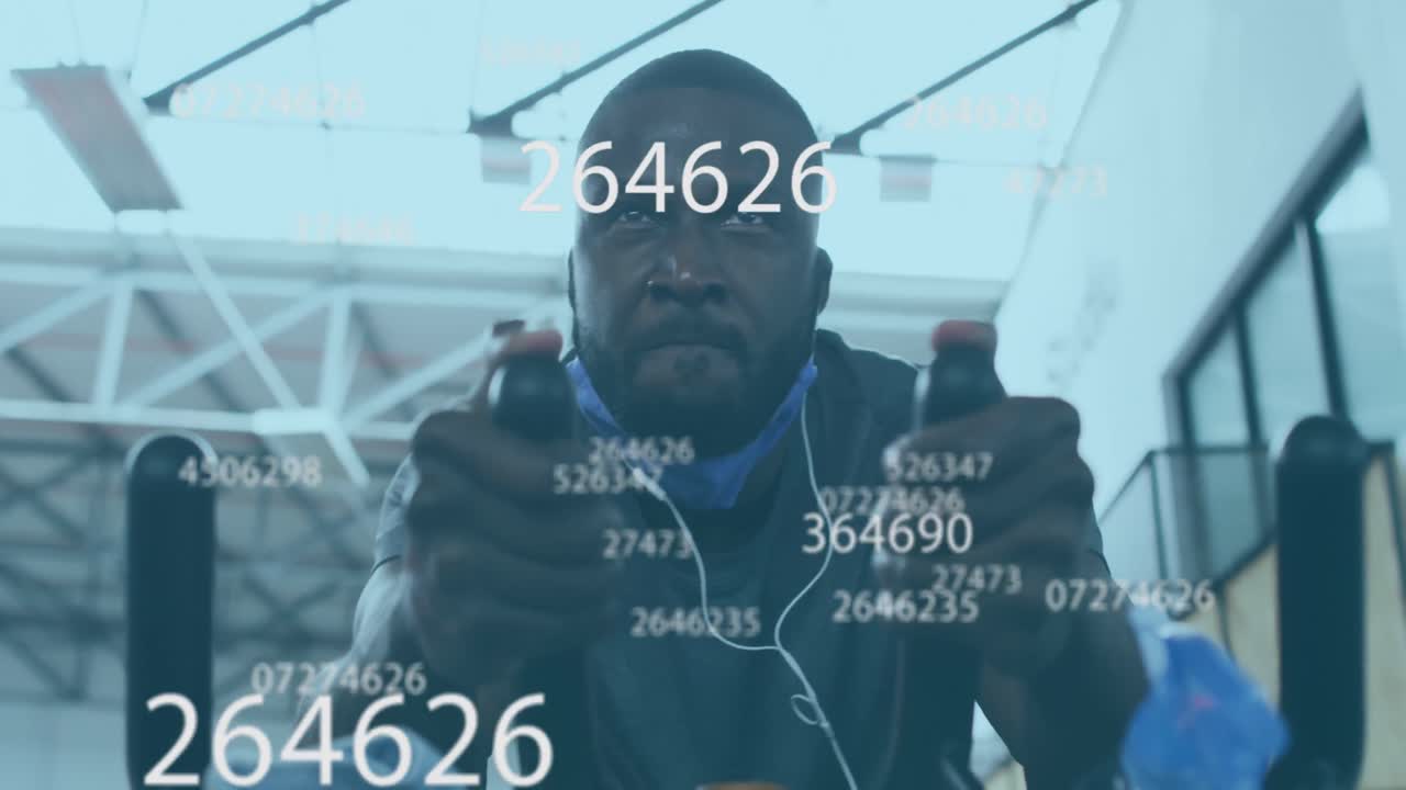 Animation of symbols changing over man with face mask exercising on elliptical bike in gym