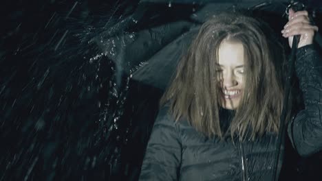 joyful girl poses with umbrella under night rain slow motion