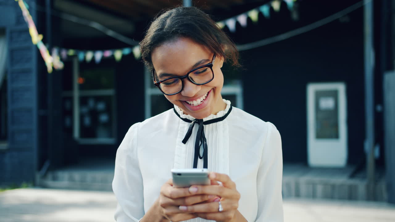 Donna sorridente che messaggia al telefono all'aperto