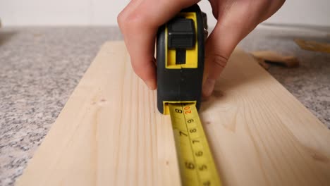 caucasian hand of handyman rolls out a yellow measuring tape, dolly in shot