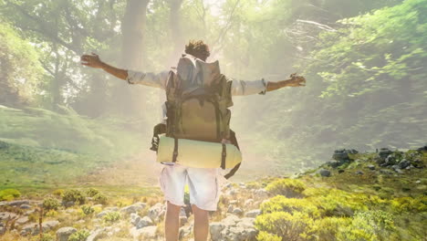 hiking with arms outstretched, backpacker over sunlit forest trail