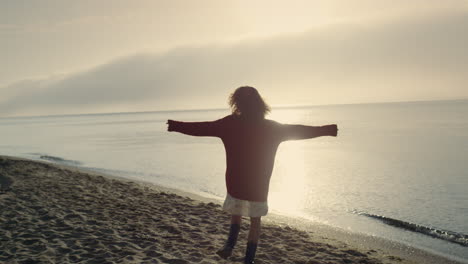 mujer emocionada dando vueltas en la playa. chica feliz bailando en la orilla del mar