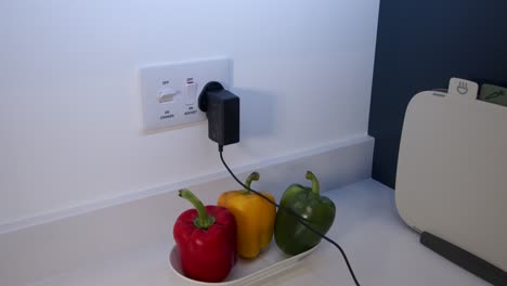 female model plugging in a power adapter plug and turning on then off a white power switch in a kitchen