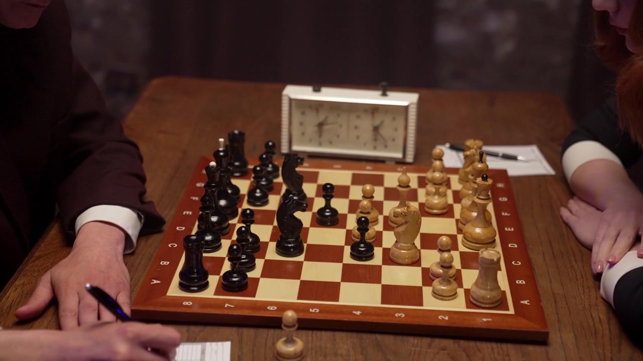 Deux personnes jouant une partie d'échecs stratégique avec une pendule.