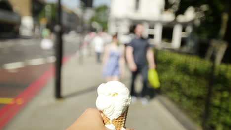 man holding ice-cream point of view walking through city