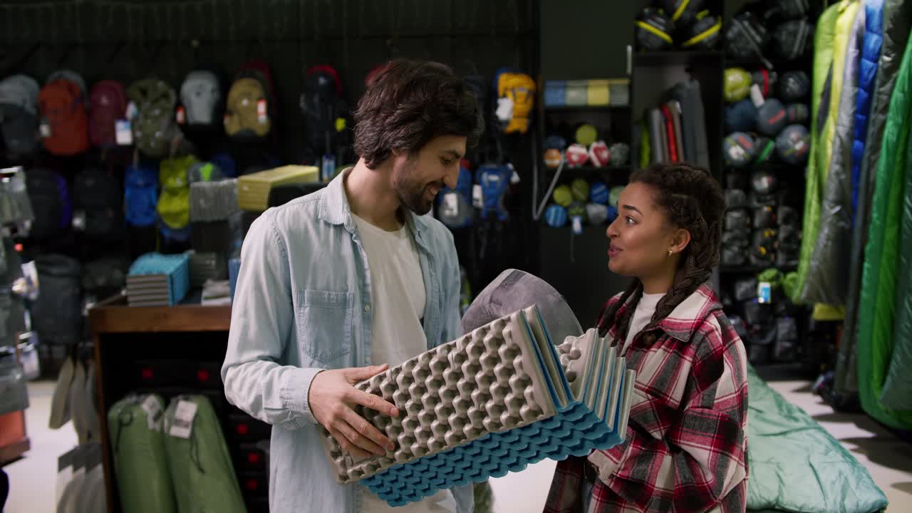 los jóvenes están eligiendo equipo de viaje en la tienda de deportes