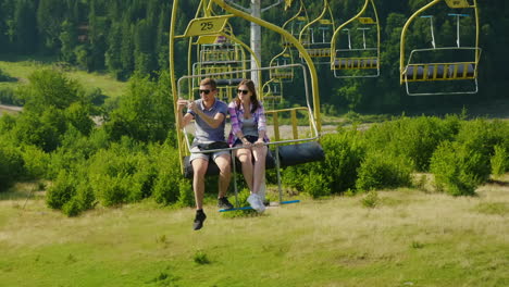 a happy young couple is riding on a ski lift photograph landscapes holidays in the mountains in summ