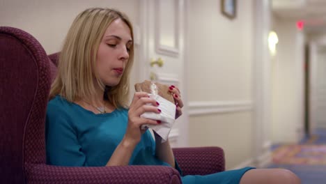 mujer joven sentada en una silla y comiendo sándwich durante el almuerzo