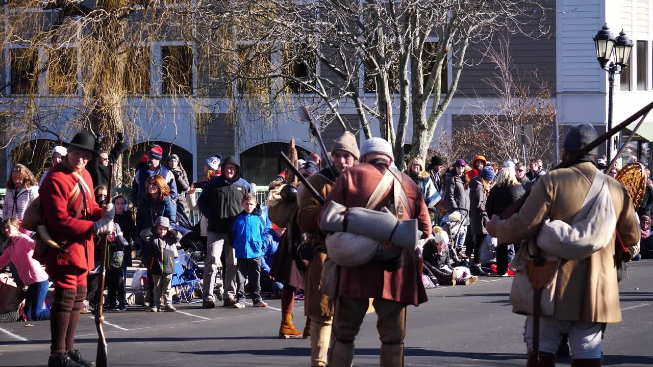 Authentically dressed pilgrims and Red Coats with flintlocks flung over their shoulder taking a break and talking to each other during the Thanksgiving Parade 2019 in Plymouth, Massachusetts