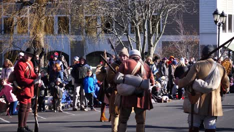 authentically dressed pilgrims and red coats with flintlocks flung over their shoulder taking a break and talking to each other during the thanksgiving parade 2019 in plymouth, massachusetts