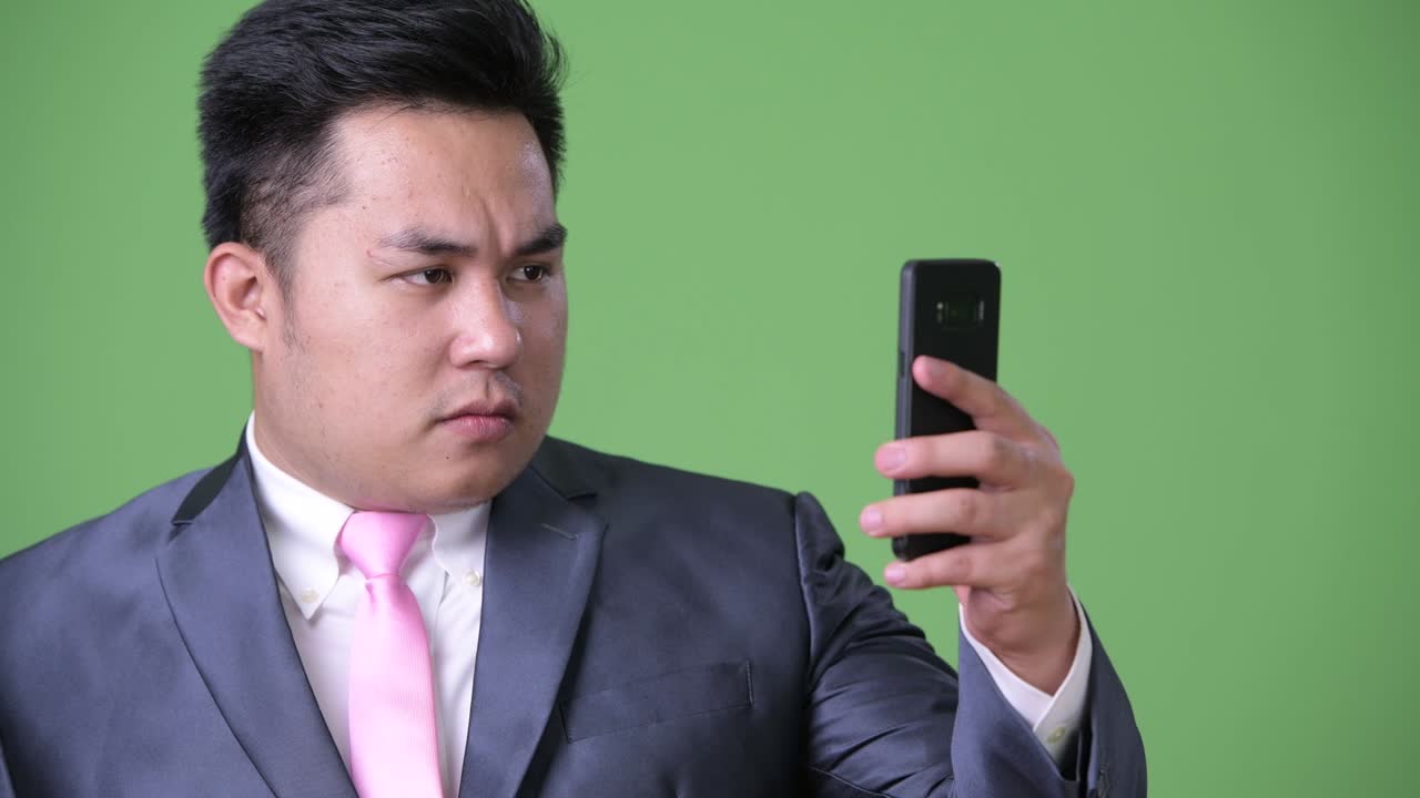 초록색 배경에 젊은 잘생긴 과체중 아시아 사업가