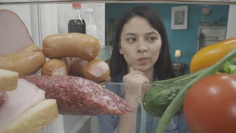 mujer mirando dentro de un refrigerador