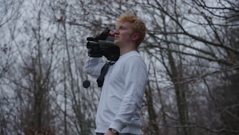 Filmmaker-walking-with-an-old-35mm-camera-on-his-shoulder-and-looks-through-viewfinder