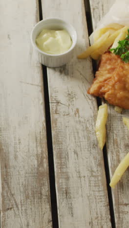 video of wrapped fish and chips with dip, on rustic table top with copy space