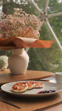 vase with autumn flowers on served low table. coffee table paired with cozy armchairs creates perfect spot to enjoy breakfast against breathtaking views of lake