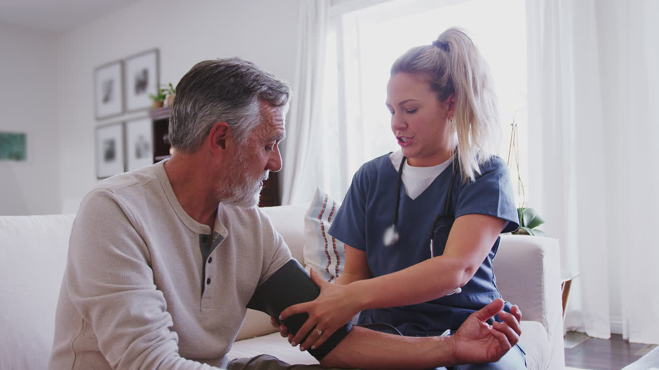 Female healthcare worker using a blood pressure meter on a senior man during a home health visit