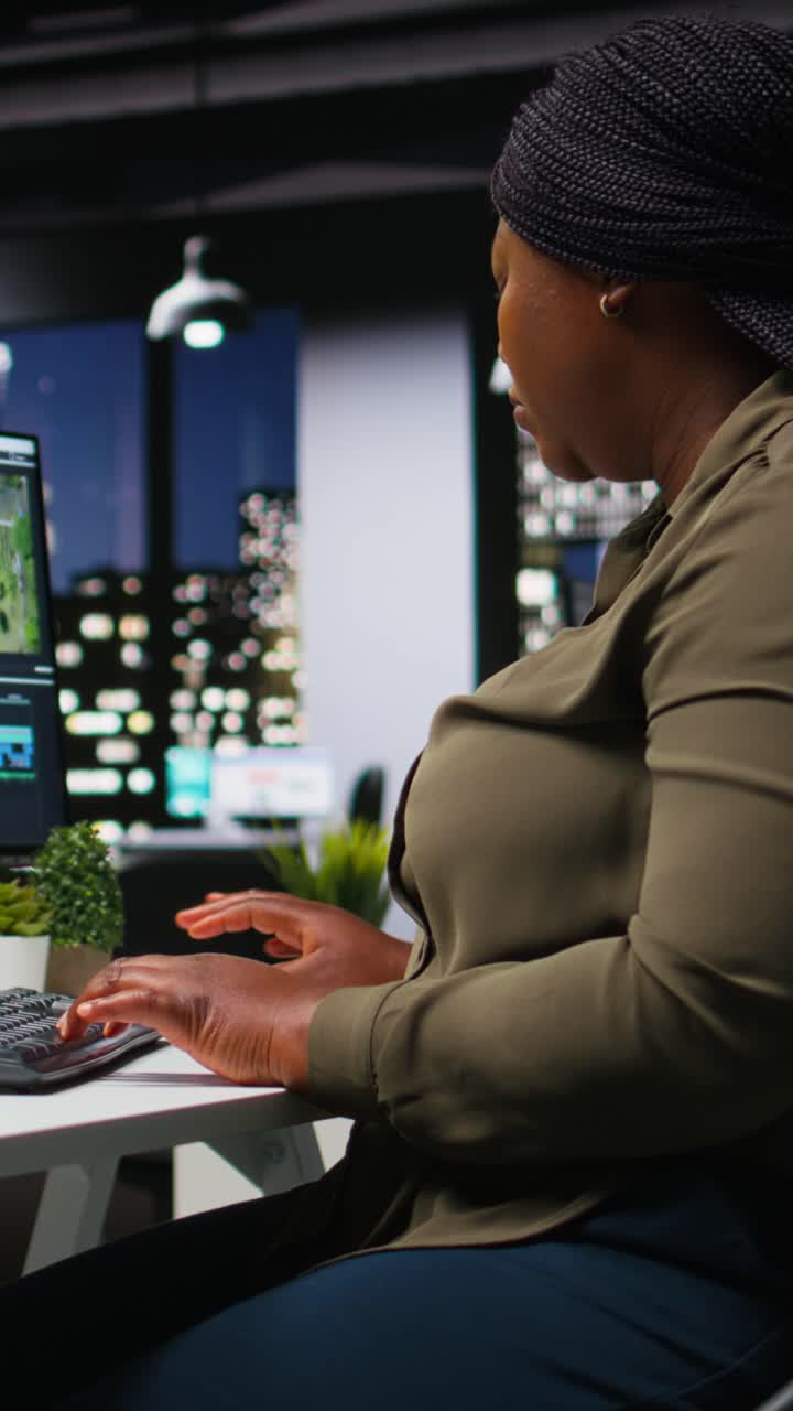 Vertical Video African american video editor working with dual monitors in modern office