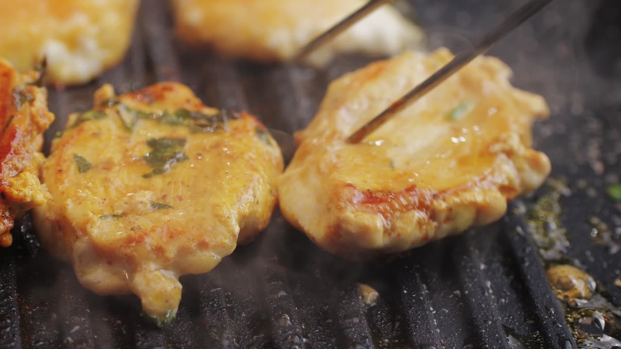 Cooking raw chicken meat in yellow turmeric spice with garlic and greens on grill close-up. Fry chicken slice on frying.pan Grilled chicken, duck, turkey kebab with vegetables.