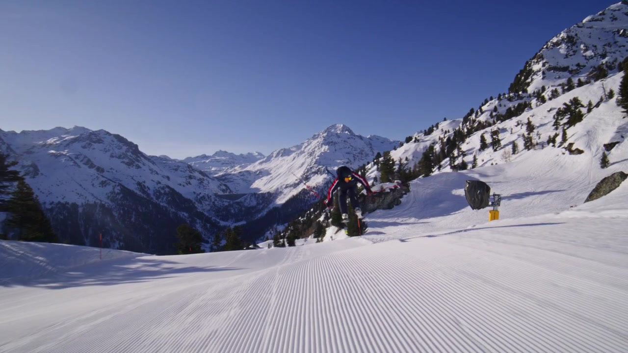 Skier carving groomed pistes at high speed in Nendaz, part of the 4 Vallées ski area in the Swiss Alps. Elite alpine skiing with powerful snow spray and precision technique.