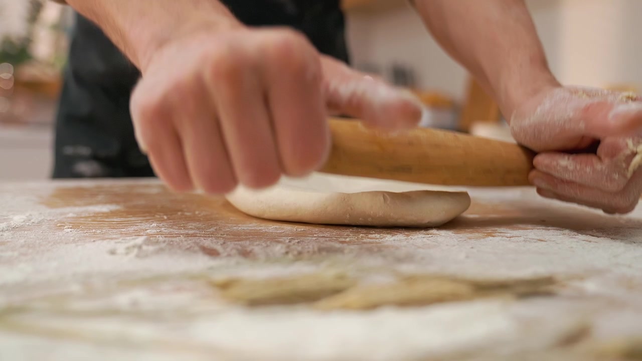 Close-up of Hands Rolling Dough with a Wooden Rolling Pin