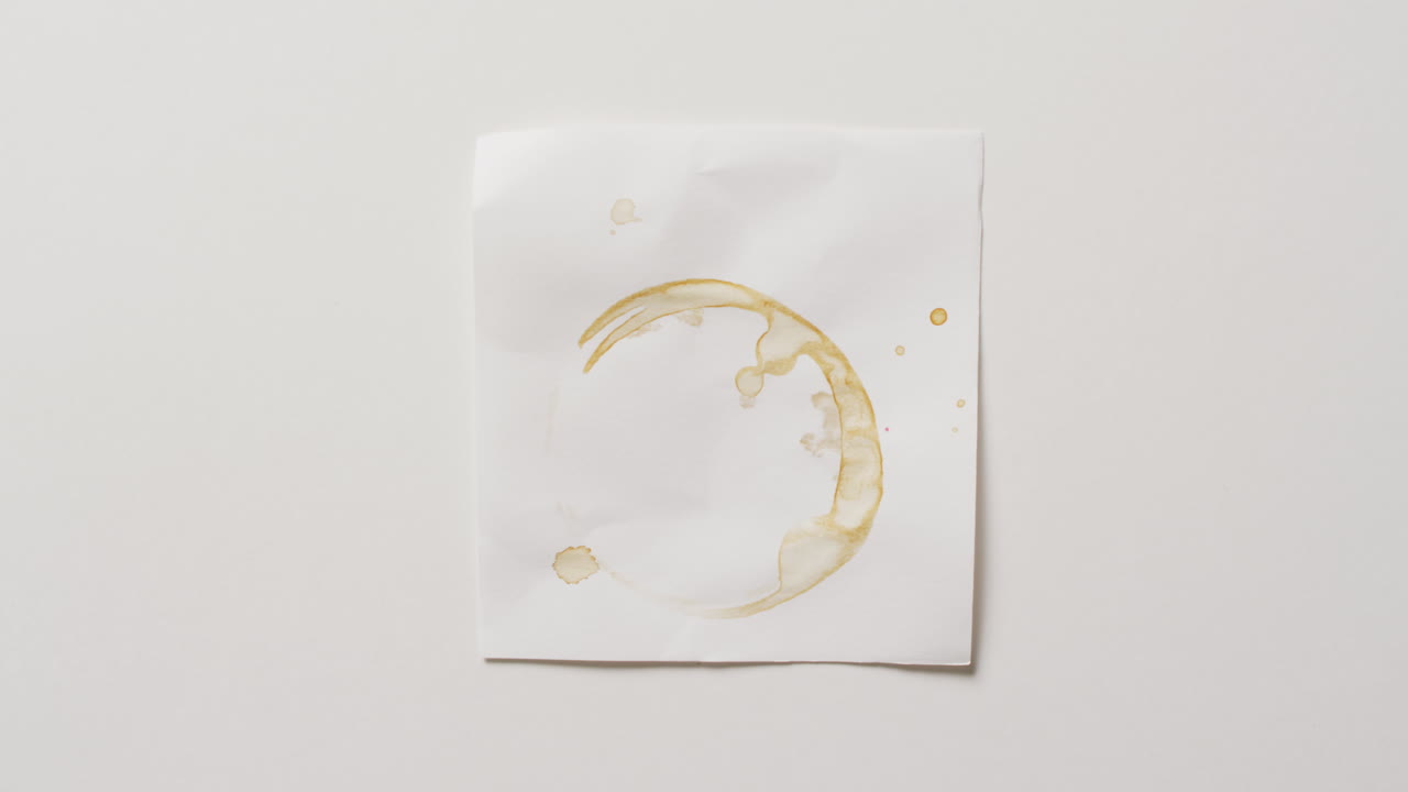video de primer plano de un pedazo de papel con mancha de anillo de taza de café sobre un fondo blanco