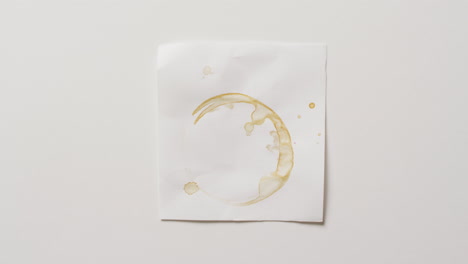 video de primer plano de un pedazo de papel con mancha de anillo de taza de café sobre un fondo blanco