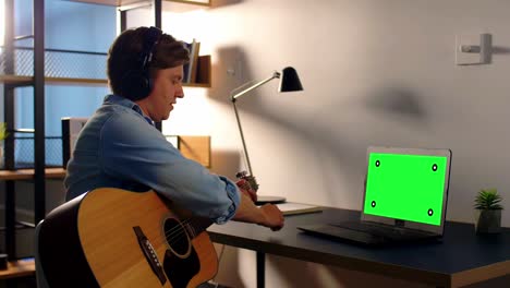hombre con auriculares tocando la guitarra en casa