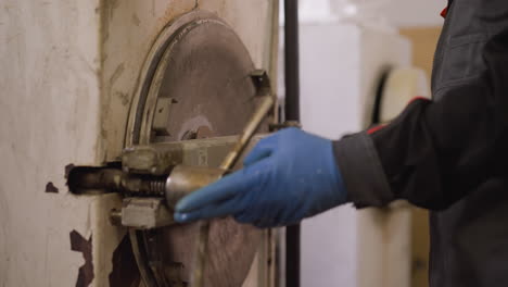 close-up of a worker's gloved hand operating a kiln door at a pottery workshop