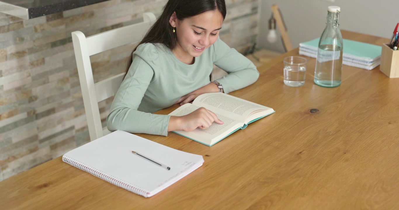 Young Woman Reading a Book at a Wooden Table