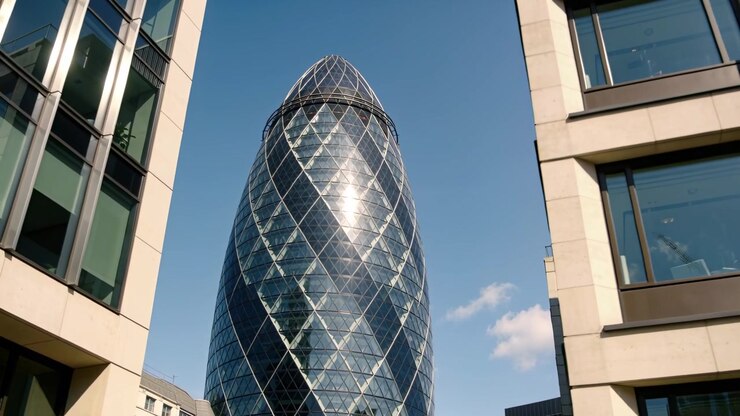 Telecamera inclinata che espone una torre di vetro a forma di uovo tra edifici per uffici, enfatizzando l'altezza della torre.