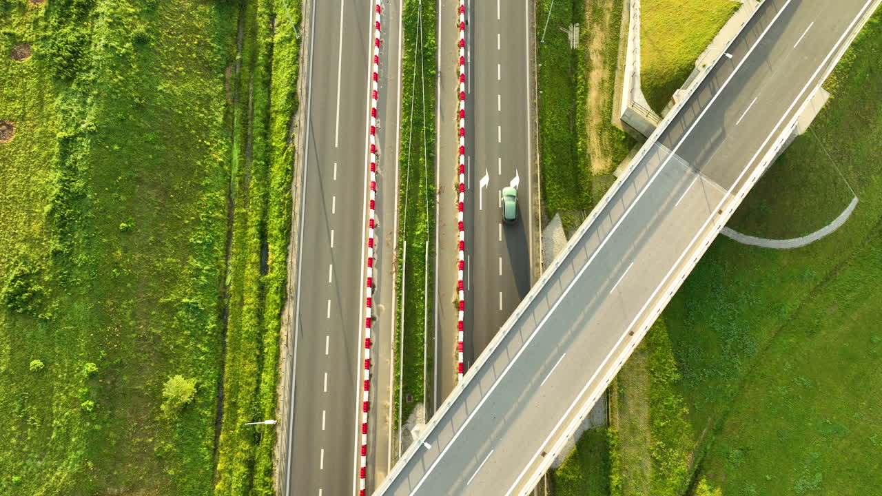 Geometric top-down aerial view of a white van driving under a highway overpass on the S6, highlighting the lines, geometry, and safety barriers