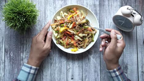 person eating a tuna salad with mixed vegetables