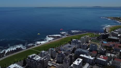 Tiro-De-Drone-De-Sea-Point,-Ciudad-Del-Cabo---Drone-Está-Volando-Sobre-El-Bulevar,-Mirando-El-Océano-Y-Algunos-Parapentes