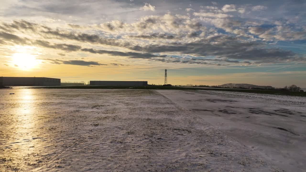 Sunset over industrial area with snow reflection and dramatic sky