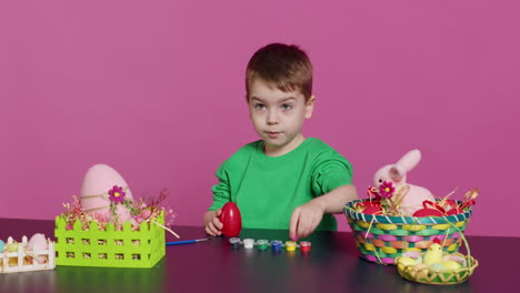 small sweet child decorating eggs with stamps and watercolor