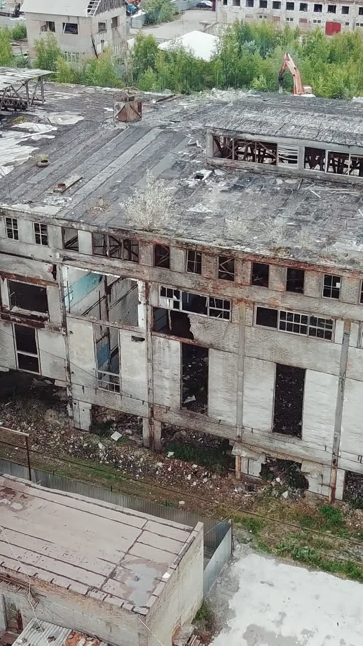 Flying over abandoned industrial factory buildings in very dilapidated condition. Old building for demolition.. Vertical video