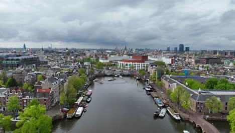 el dron está volando hacia adelante sobre el canal de ámster mirando hacia el centro de la ciudad y la ópera nacional y el ballet en un día nublado en ámsterdam los países bajos imágenes aéreas 4k