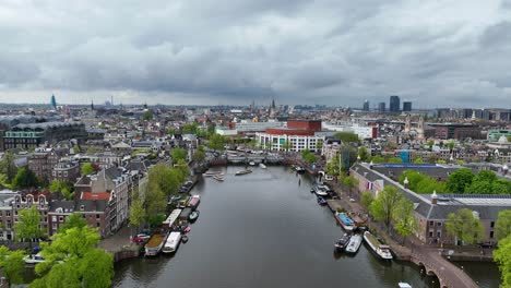 the drone is flying forward over the amster canal looking towards the city centre and the national opera and ballet on a cloudy day in amsterdam the netherlands aerial footage 4k