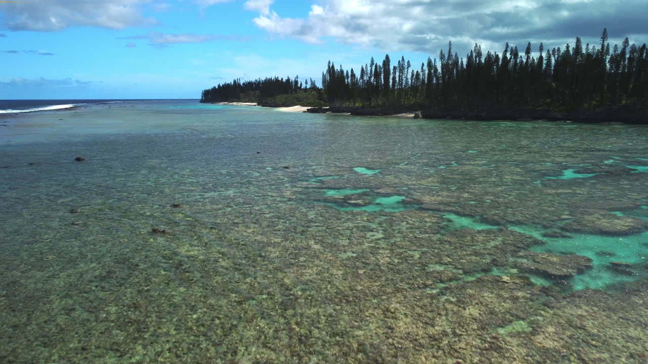 Low flyover above coral reef in pristine, shallow water off coast of Maré Island
