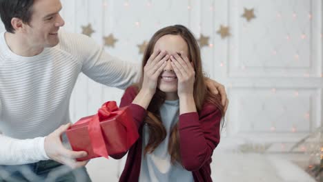 mujer alegre cerrando los ojos con las manos en una casa de lujo. pareja sonriente abrazándose