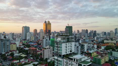 golden tower and high-rise buildings in downtown phnom penh, cambodia at sunset - aerial