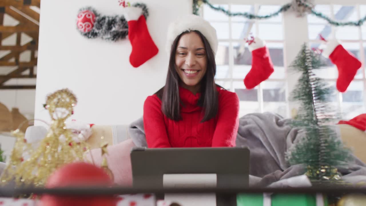 mujer biracial con sombrero de santa haciendo una videollamada