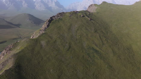 Cinematic-drone-shot-of-the-Kakshaal-Too-mountain-range-in-Kyrgyzstan,-starting-downward-then-tilting-up-to-reveal-mountains