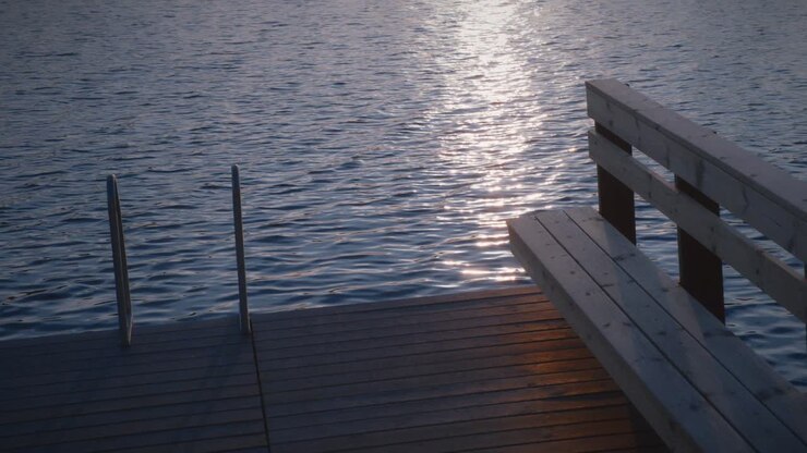 Scala e panca di legno su un pontile balneare in un lago calmo in Svezia.