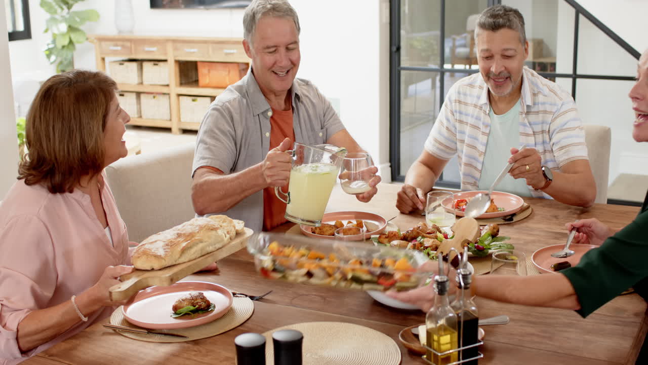 Sharing meal, senior friends enjoying lunch together at dining table