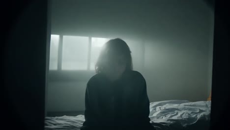 a woman sitting on a bed in a dark room