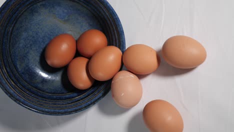huevos de gallina derramándose de un tazón azul - quizás ingredientes para hornear